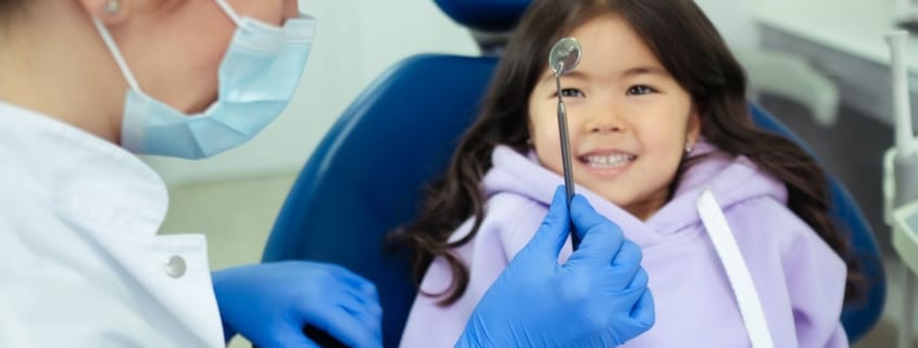 Framingham Family Dentist - Child Checkup - Unique Dental of Framingham A dentist and a smiling child during a friendly dental check-up.