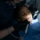 Preventive Care Framingham Family Dentist - Unique Dental of Framingham Child patient receiving dental care while a dentist examines her mouth with tools and a mirror, wearing a blue bib and gloves