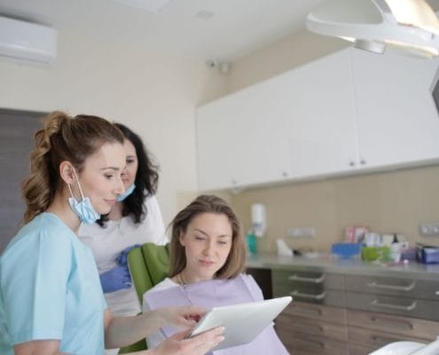 Dental team reviewing a tablet with a patient seated in a dental chair in a modern clinic.
