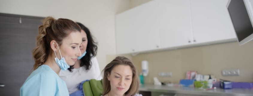 Choosing the Right Framingham Family Dentist - Unique Dental of Framingham Dental team reviewing a tablet with a patient seated in a dental chair in a modern clinic.